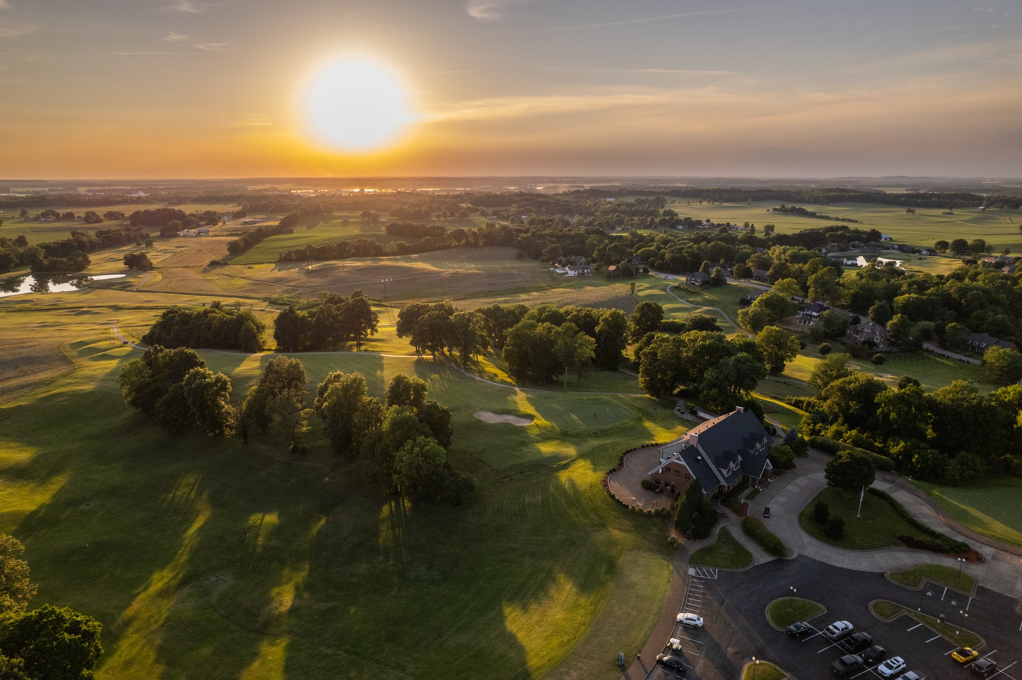 Aerial view of The Pearl Club golf course in Owensboro, Kentucky at sunset, showing fairways, clubhouse, and surrounding landscape.